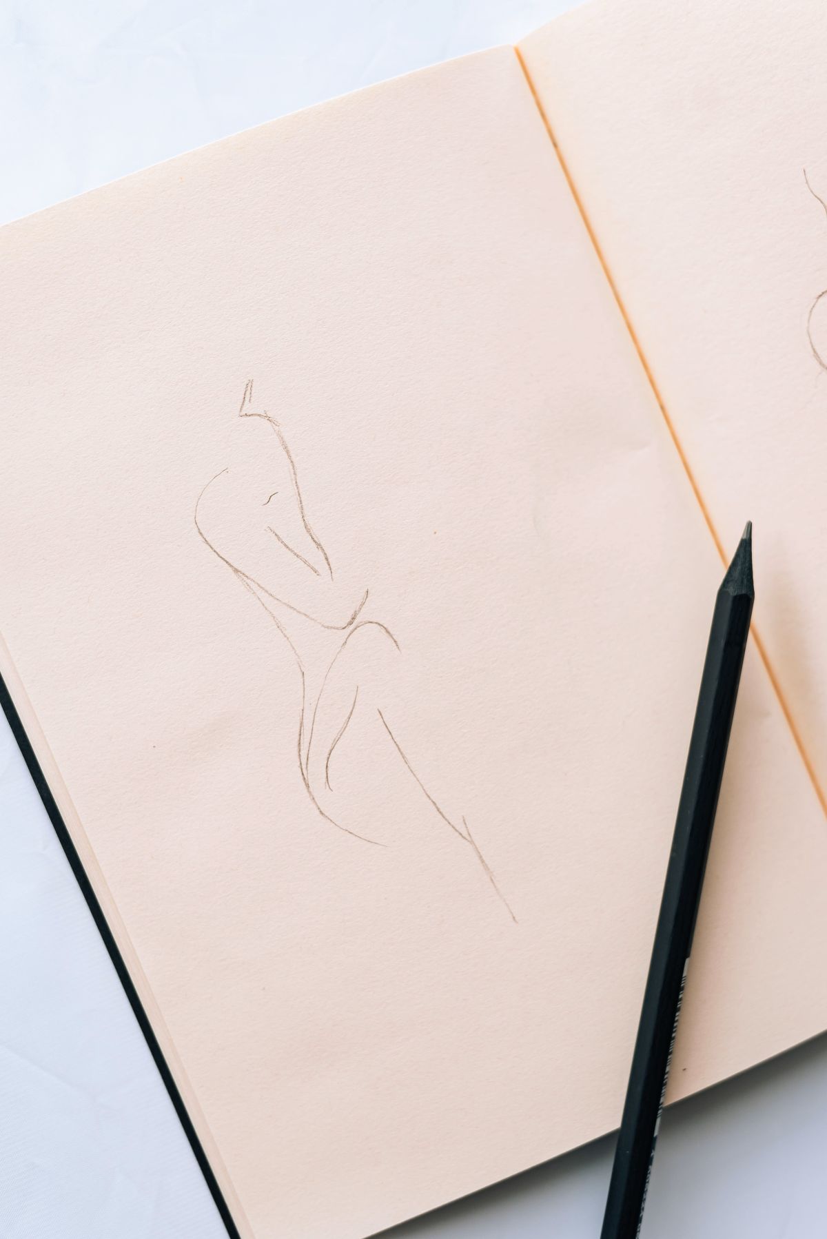 Apprendre à dessiner sans se ruiner : par où commencer quand on part de zéro carnet de croquis ouvert avec un dessin au trait et un crayon